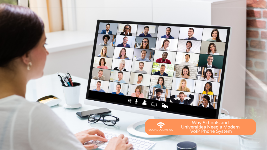 A woman sitting at a desk looking at a computer screen showing a large video conference call with dozens of participants. In the bottom right, an orange banner features the Social Comms UK logo and the text "Why Schools and Universities Need a Modern VoIP Phone System."