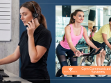 Customer service representative wearing a headset and working at a desk next to people using exercise bikes in a gym.