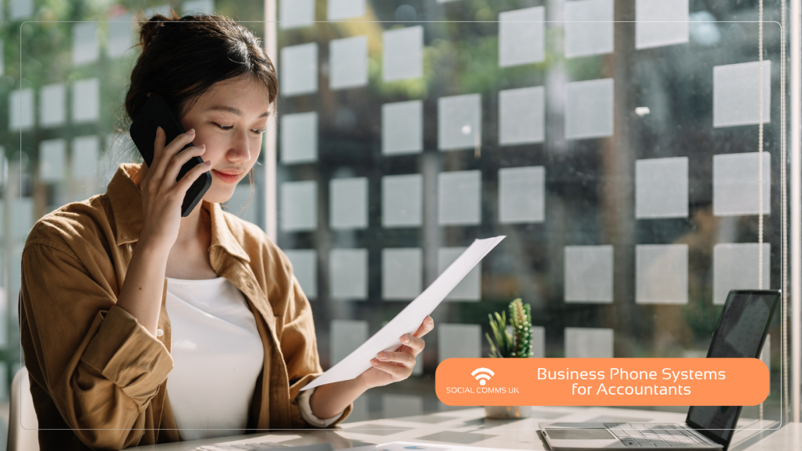 Professional accountant reviewing documents while talking on a business phone system in a modern office.