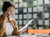 Professional accountant reviewing documents while talking on a business phone system in a modern office.